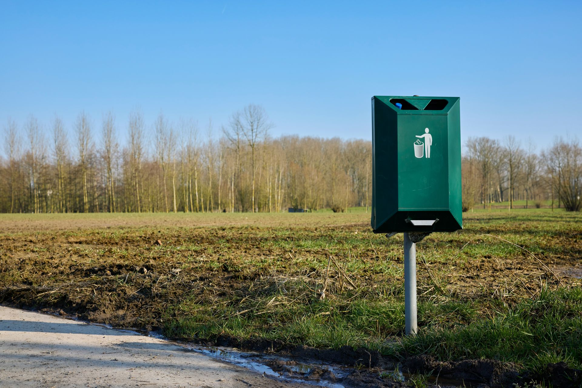Green dog waste bin in a rural field